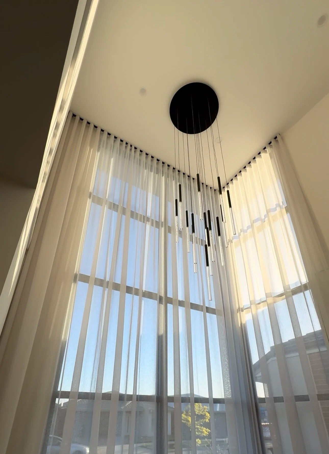 Automated sheer curtains across tall windows in a modern home