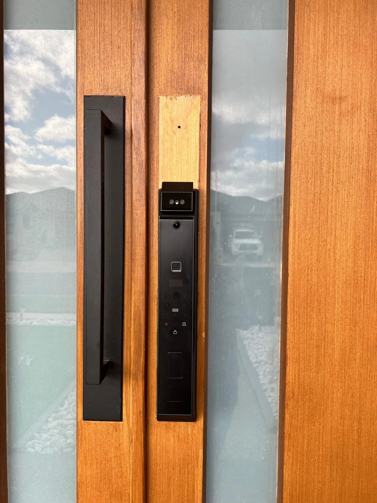 Black smart lock installed on a warm timber entrance